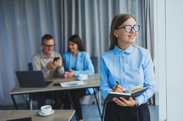 A young woman with a gray notebook in her hands Notepad for recording cases Businesswoman makes notes with a pen