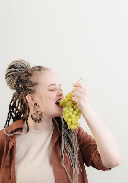 Young woman with green grape on white background