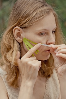 Giovane donna con nastri verdi sul viso taping estetico viso