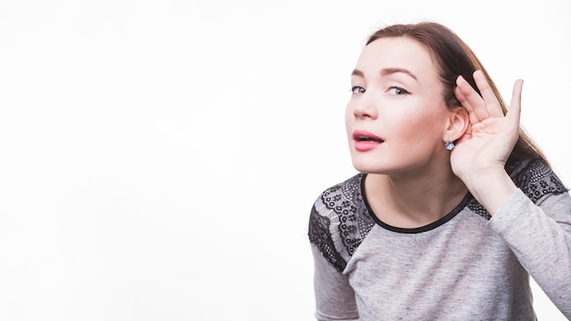 Photo young woman with hand behind ear listening closely