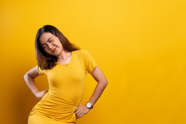 Foto giovane donna con le mani sul fianco seduta sullo sfondo giallo