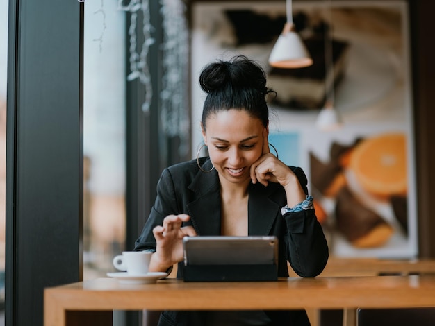 Young woman with happy face sitting in coffee shop at wooden table, drinking coffee and using laptop.Coffee break .