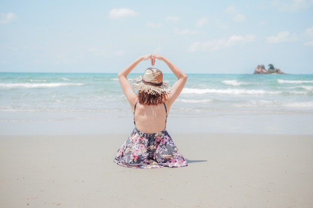 Una giovane donna con cappello è seduta sulla spiaggia