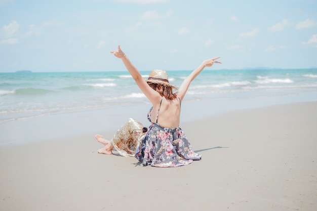 Una giovane donna con cappello è seduta sulla spiaggia