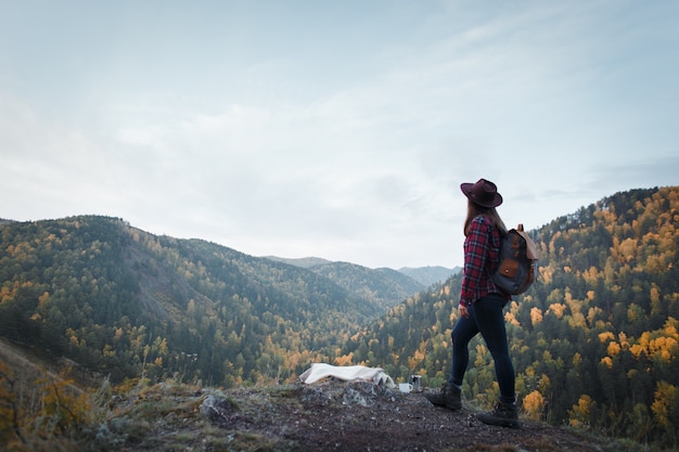 Young woman with a hat on the mountain peak