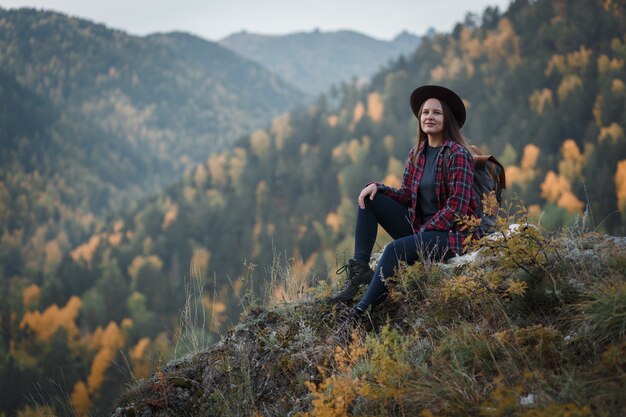 Young woman with a hat on the mountain peak