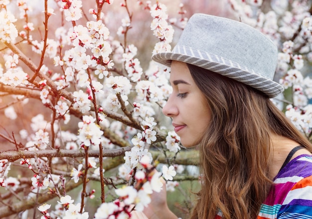 Young woman with hat smelling the cherry blossom