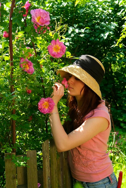Young woman with a hat smells on a rose rosa moyesii marguerite hilling