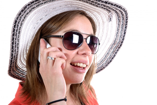 帽子とサングラスの電話を持つ若い女性帽子とサングラスの電話を持つ若い女性