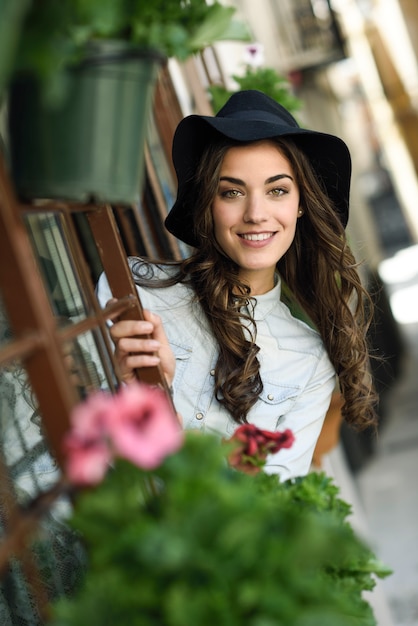 Young woman with hat in urban background wearing casual clothes