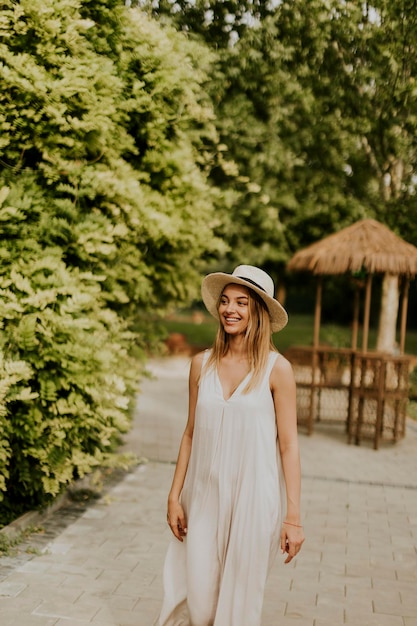 Giovane donna con cappello che cammina nel giardino del resort