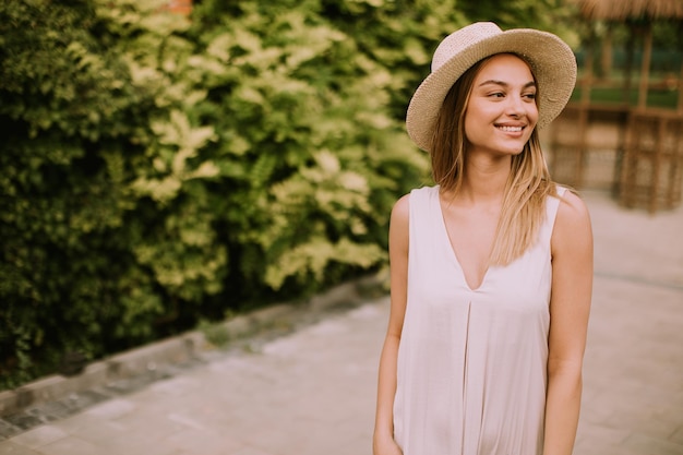 Giovane donna con cappello che cammina nel giardino del resort