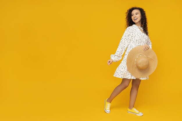 Young woman with hat on yellow background