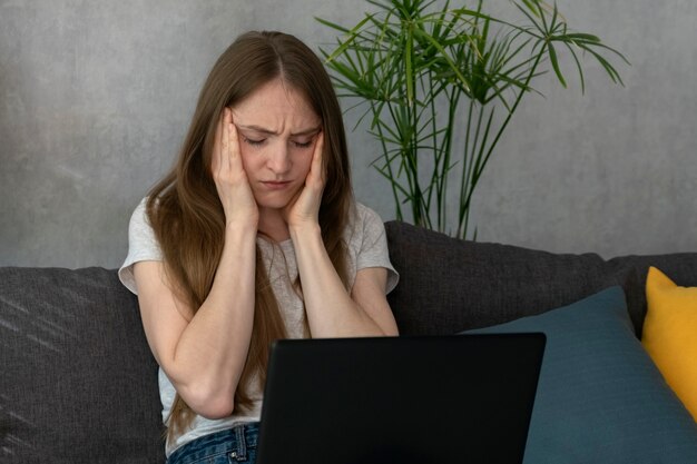 Young woman with headache is trying to concentrate at work. Migraine headaches during working day.