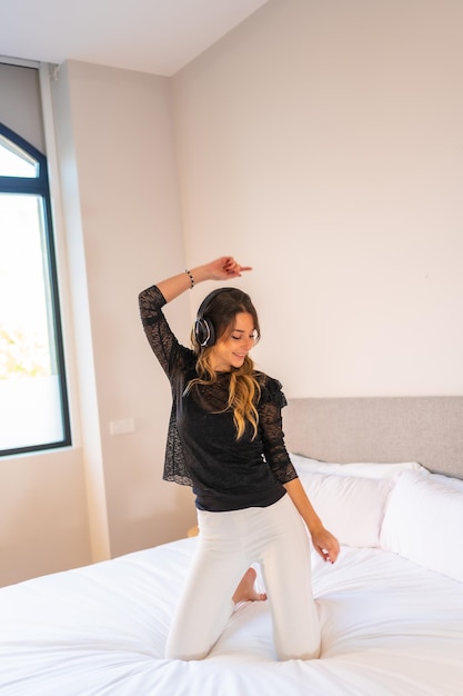 Young woman with headphones enjoying music on top of bed