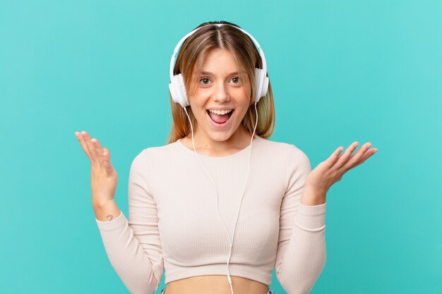 Young woman with headphones feeling happy and astonished at something unbelievable