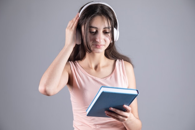 本を保持しているヘッドフォンを持つ若い女性