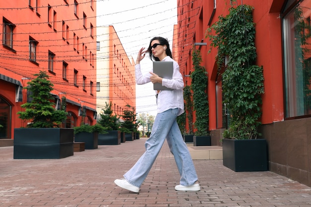 A young woman with headphones and a laptop goes to the office to work