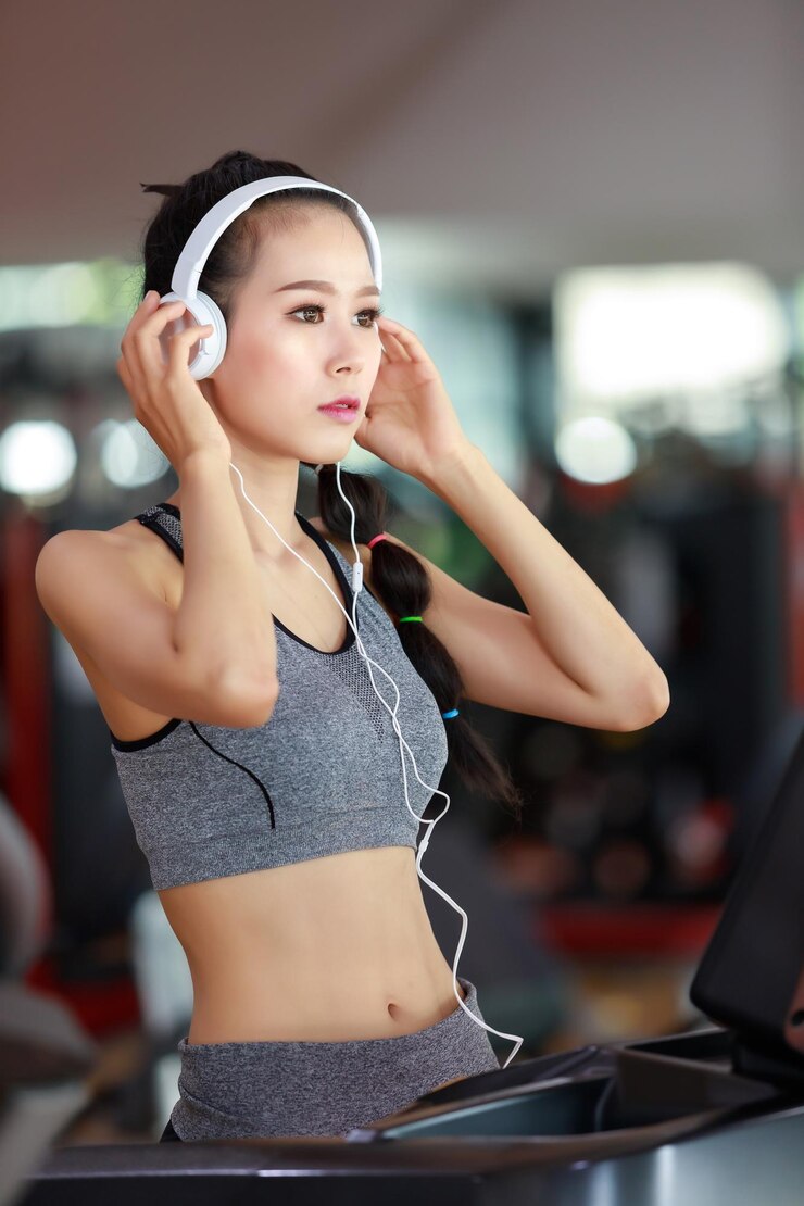Photo ヘッドフォンをかけた若い女性がジムで目をそらしている