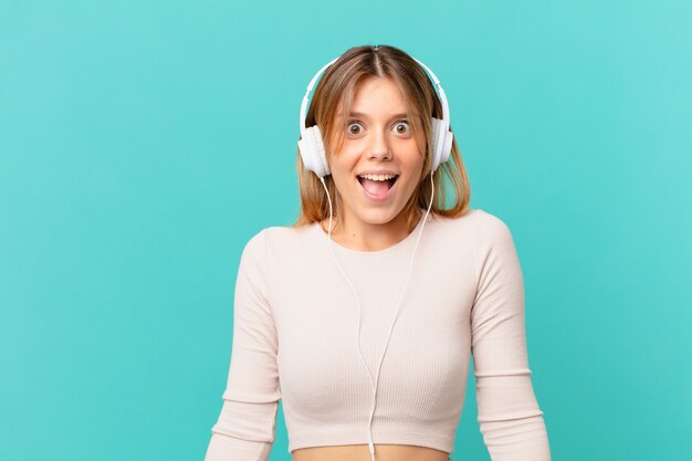 Young woman with headphones looking happy and pleasantly surprised