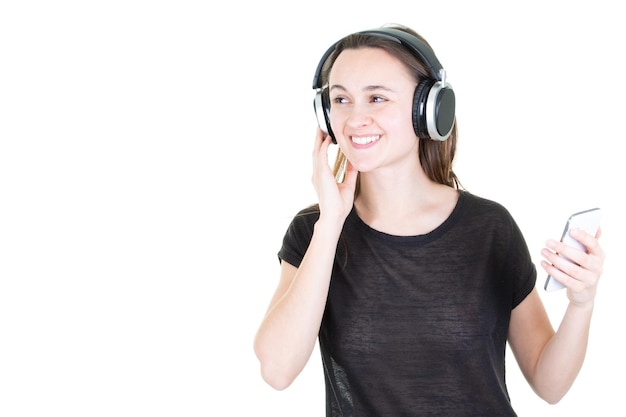 Young woman with headphones looks at phone looks left copy space