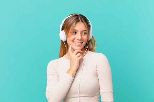 Young woman with headphones smiling with a happy, confident expression with hand on chin