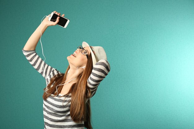 Young woman with headphones on turquoise background