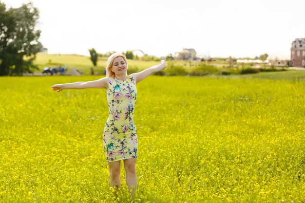 Young woman with her arms wide spread is enjoying in the sunny summer day, rear view