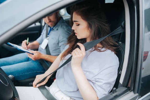 Foto giovane donna con il suo istruttore di auto in auto