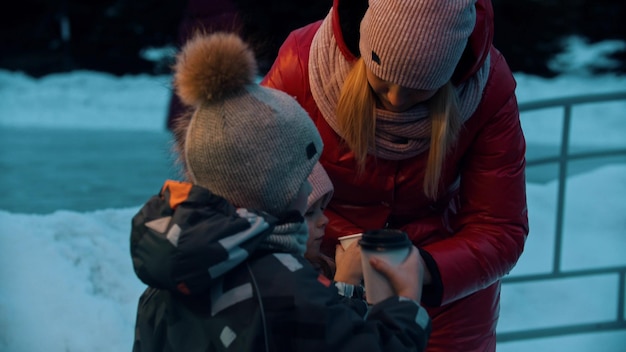 Young woman with her children drinking hot drinks