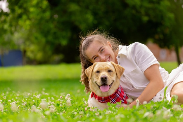 Young woman with her cute yellow labrador outside lovely pet
animal love concept