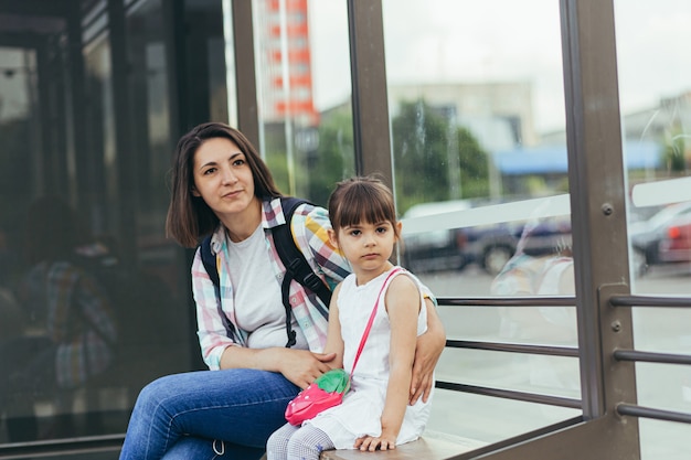 Молодая женщина с дочерью ждут автобус на автовокзале.