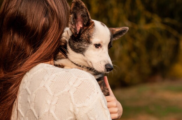 秋の色で彼女の犬を持つ若い女性