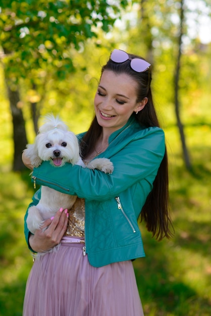 彼女の犬と若い女性。子犬の白い犬が飼い主と一緒に走っています。友情、動物、自由についての概念。