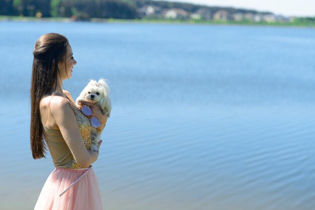 彼女の犬と若い女性。子犬の白い犬は飼い主と一緒に走っています。友情と動物についての概念。