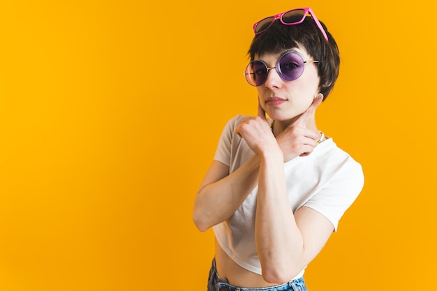 Young woman with her hands crossed under her chin wearing two pairs of sunglasses