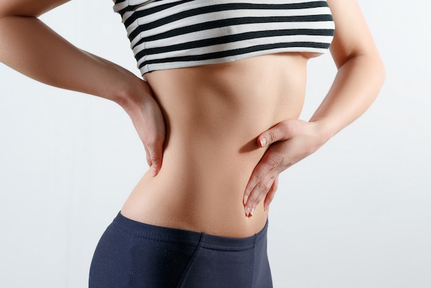 Young woman with her hands on her back and abdomen