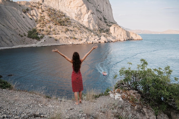 Una giovane donna con le mani all'aria aperta sullo sfondo del mare posto per il testo