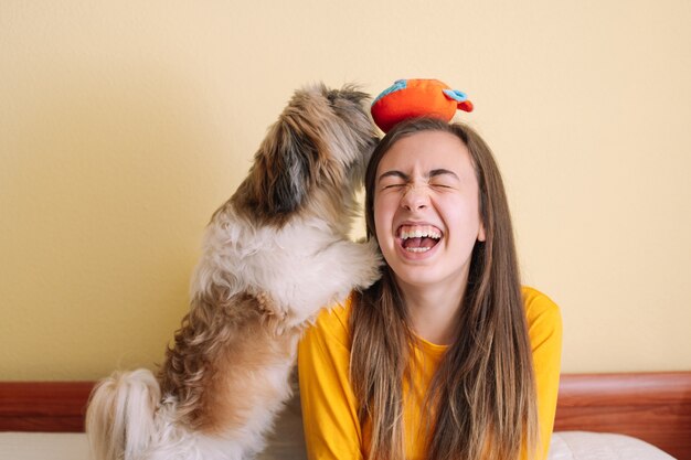 Foto giovane donna con il suo cane che gioca sul letto