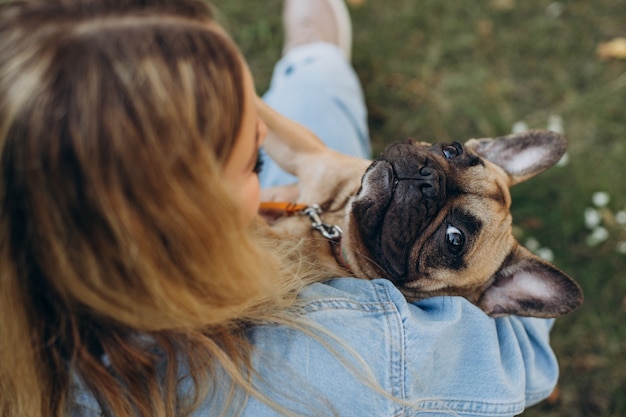 Giovane donna con il suo animale domestico bulldog francese in park