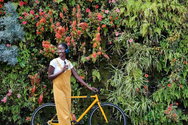 아이스크림을 들고 있는 젊은 여성과 수직 정원 개념 원예 라이프스타일 야외 옆에 있는 노란색 자전거