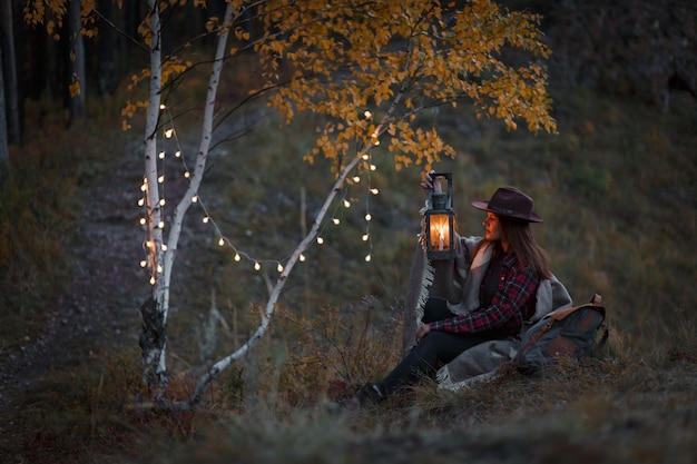숲에서 등유 램프를 가진 젊은 여자