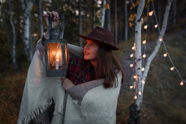 Young woman with a kerosene lamp in the forest