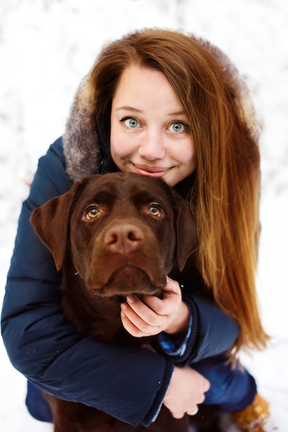 Young woman with labrador dog in winter forest