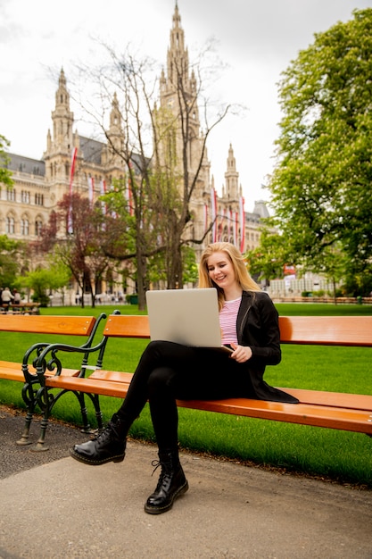 비엔나, 오스트리아에있는 공원에서 벤치에 노트북을 가진 젊은 여자