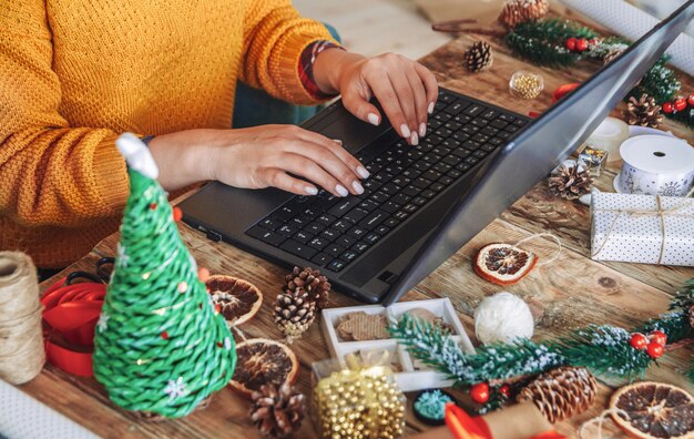 ノートパソコンを持つ若い女性は新年の贈り物を選択します