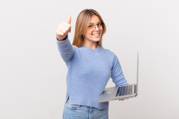 Young woman with a laptop feeling proud,smiling positively with thumbs up