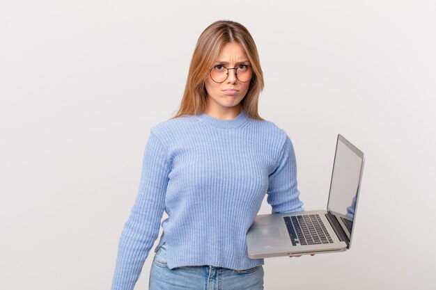 Young woman with a laptop feeling sad and whiney with an unhappy look and crying