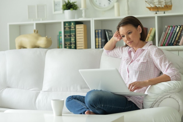 Young woman with laptop on her knees