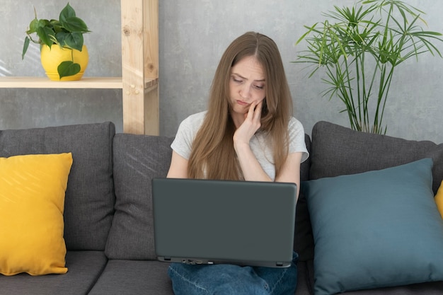 Young woman with laptop in is thinking about solving work issue. Business woman freelancer working remotely.